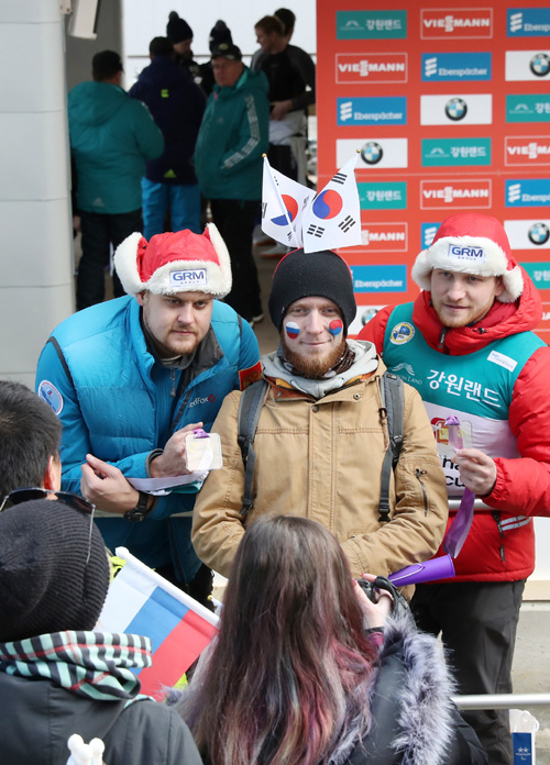 A fan with Russian and Korean flags on his cheeks poses for a picture with Alexander Denisyev and Vladislav Antonow, the doubles winners in the Viessmann Luge World Cup Nations Cup after the medal ceremony at the Alpensia Sliding Center in Pyeongchang, Gangwon-do Province, on Feb. 17.